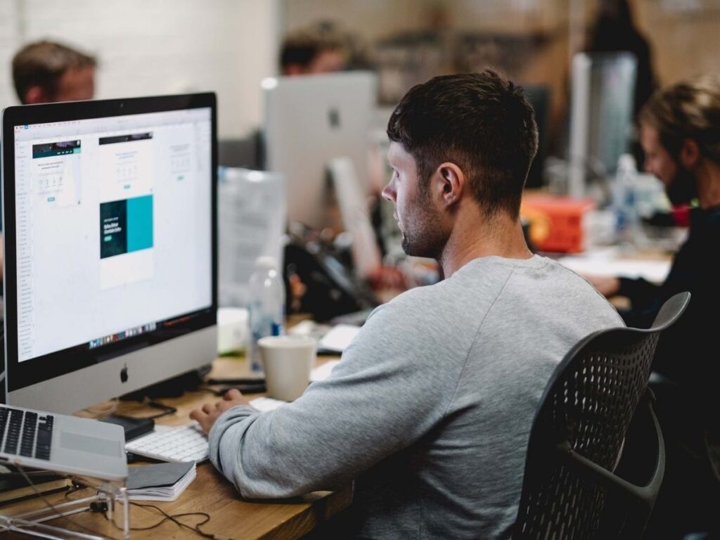 Man working on computer in busy office.