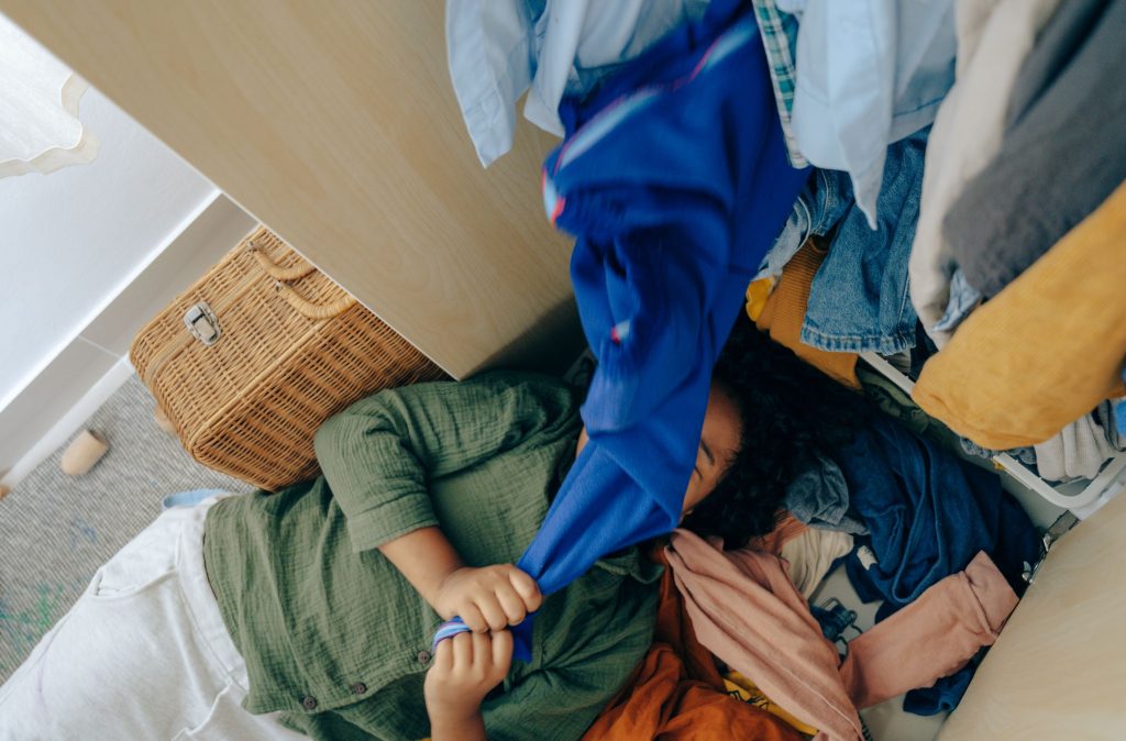 girl amongst clutter of wardrobe clothes